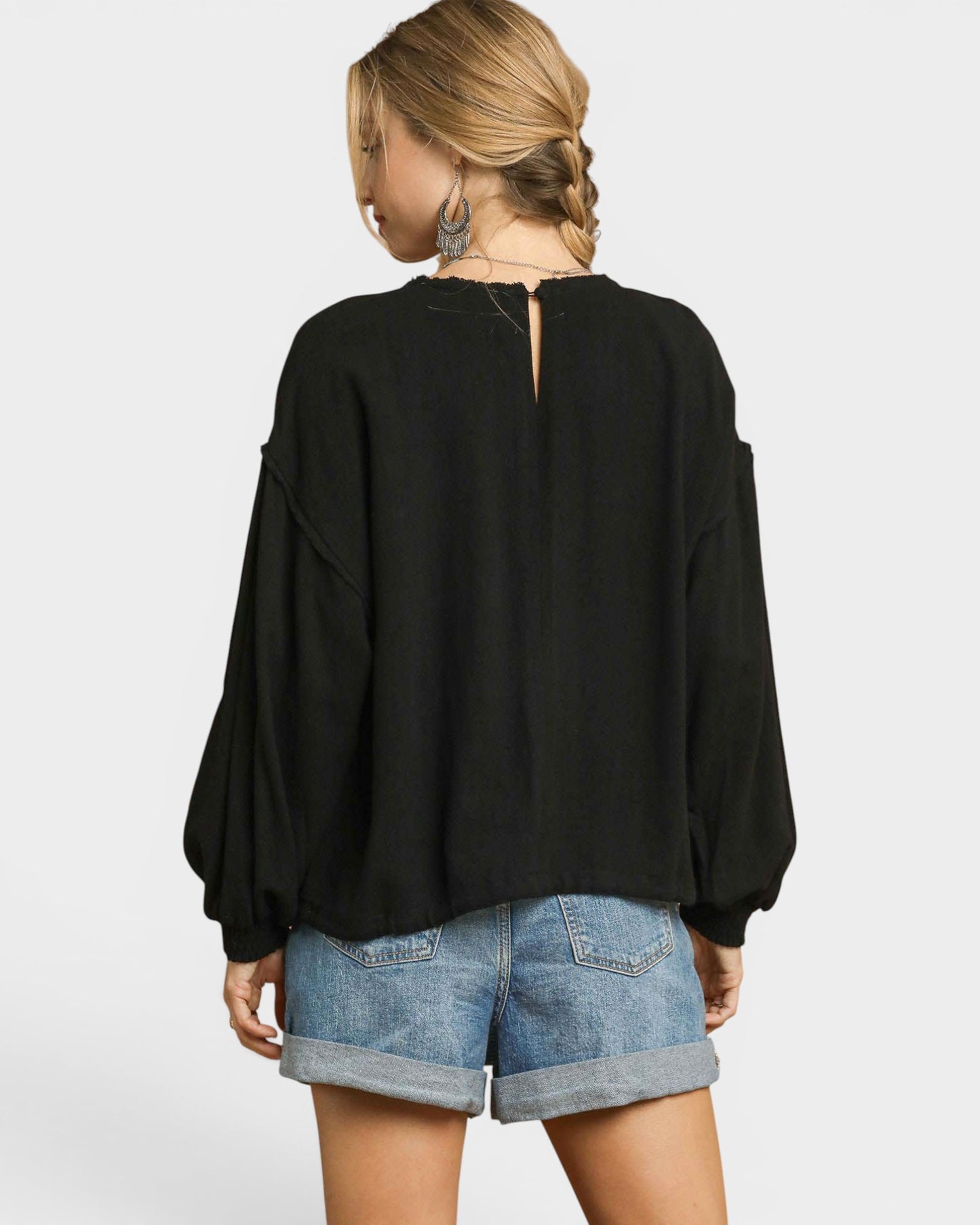 Person wearing a black top and denim shorts on a white background