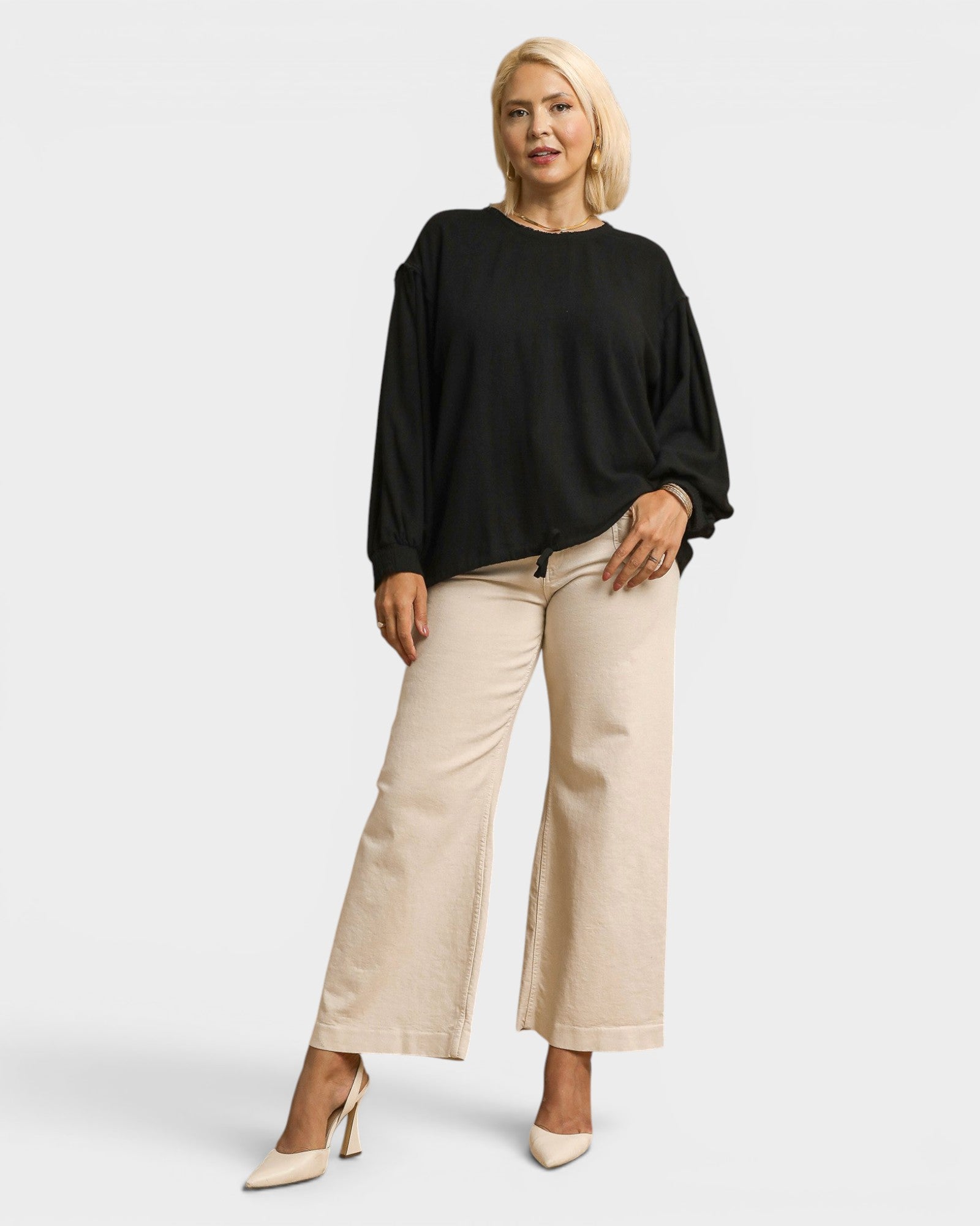 Woman wearing a black top and beige pants on a white background