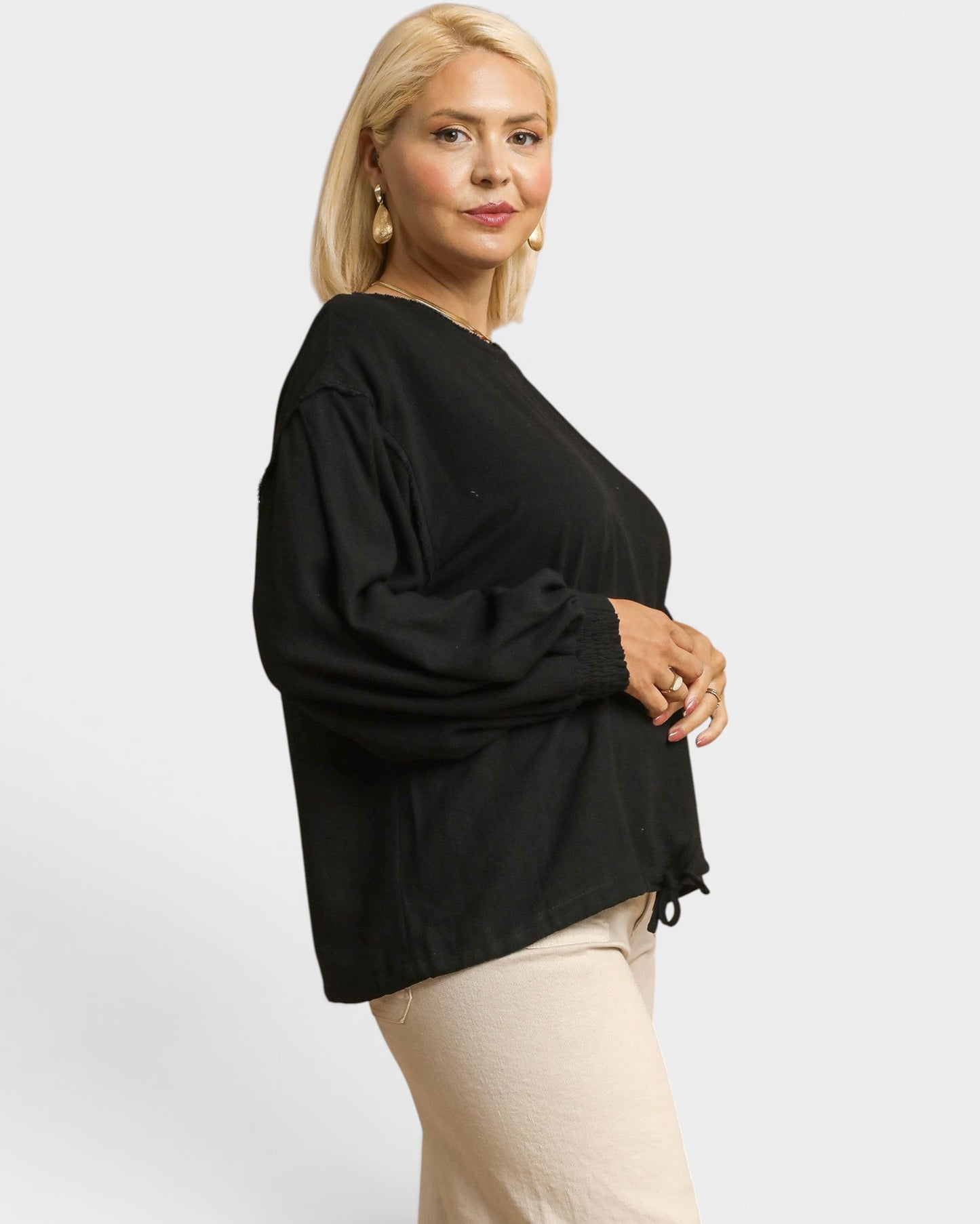 Woman wearing a black top and beige pants on a white background