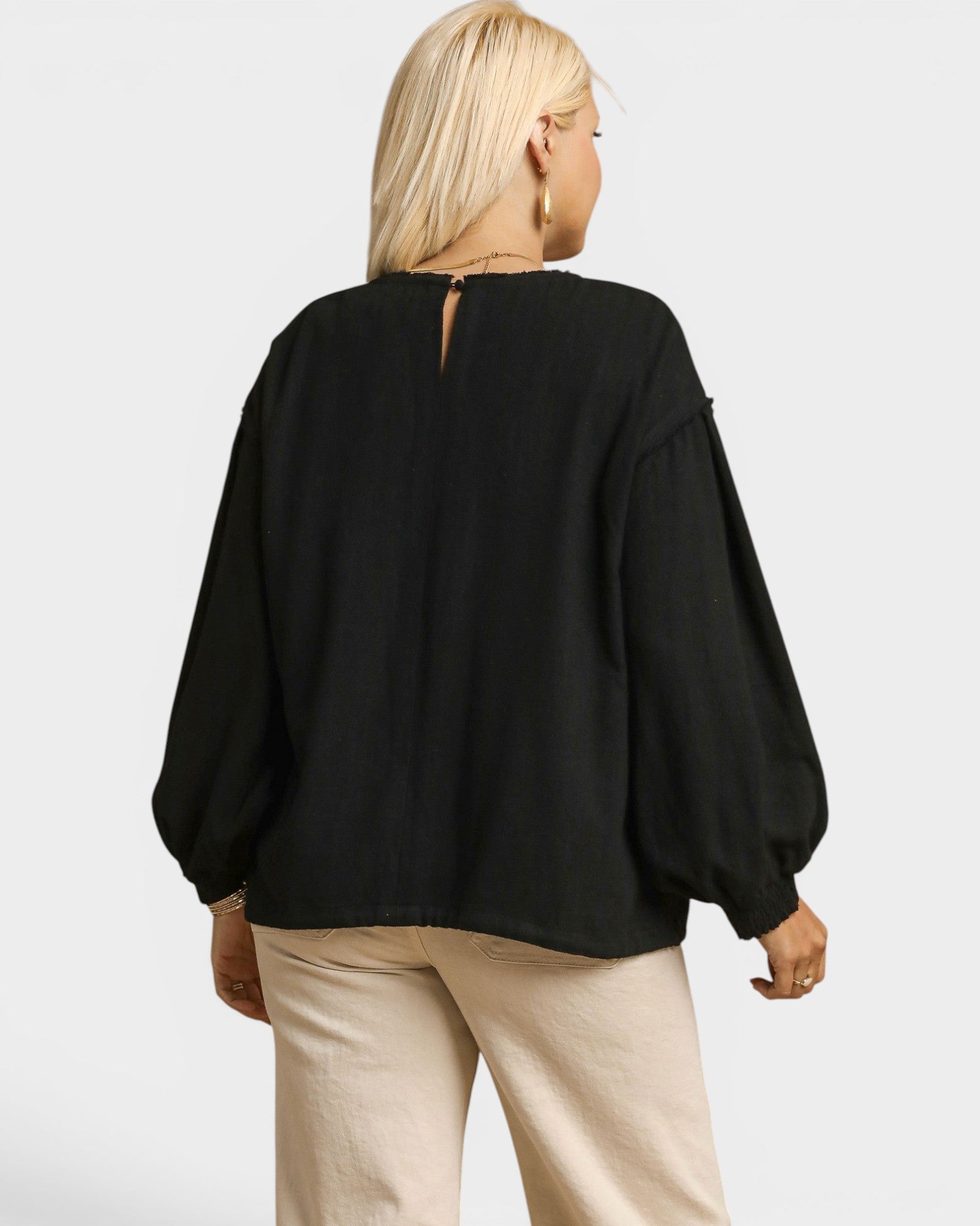 Person wearing a black blouse with balloon sleeves on a white background