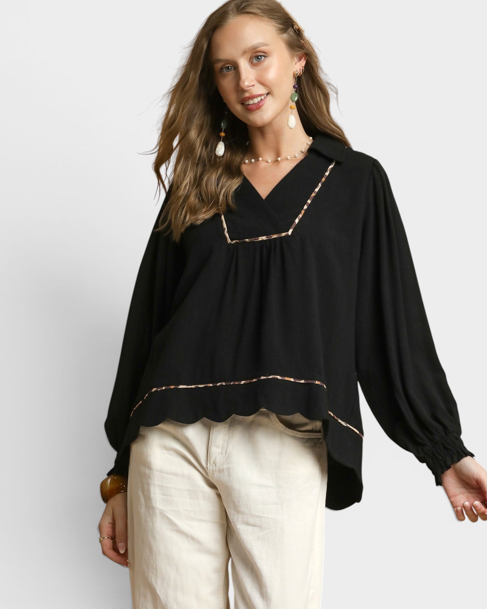 Woman wearing a black blouse with gold trim on a white background