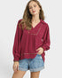 Woman wearing a burgundy blouse with long sleeves and denim shorts on a white background