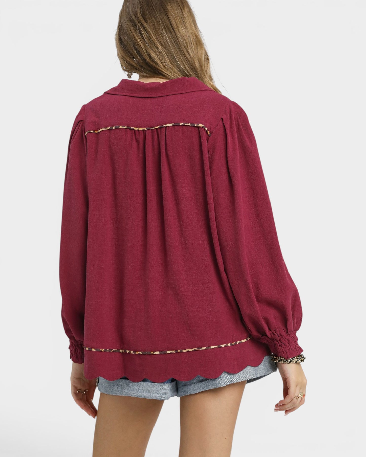 Red blouse with scalloped trim worn by a person on a white background