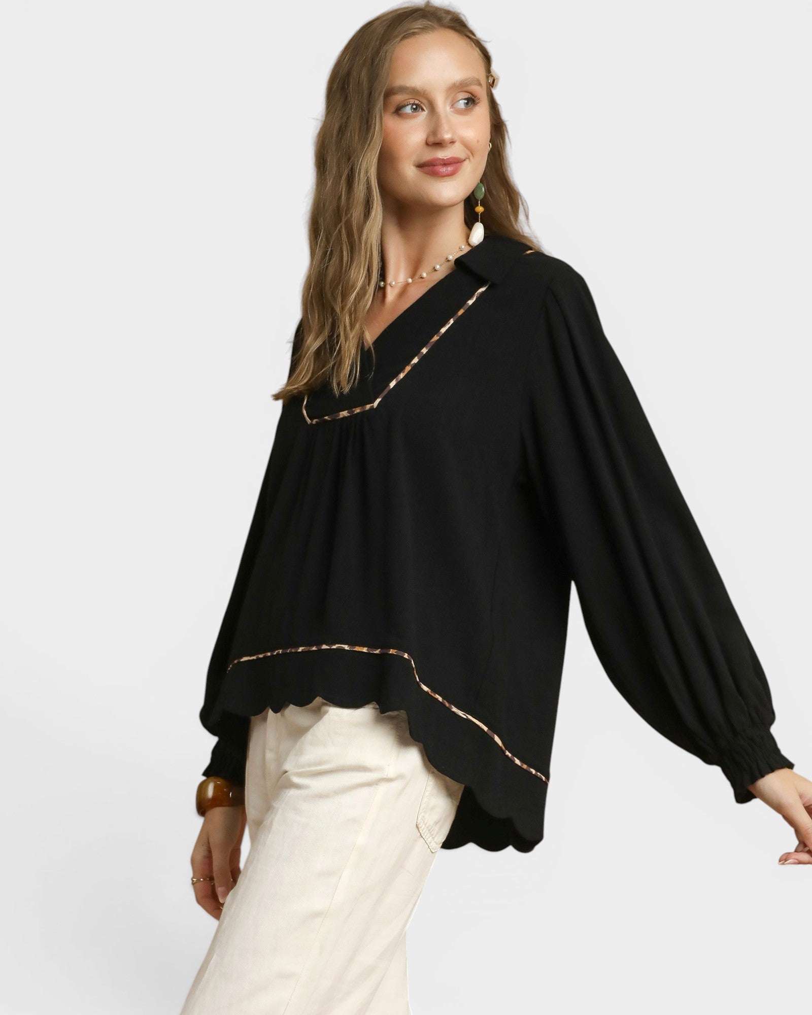 Woman wearing a black blouse with gold trim on a white background