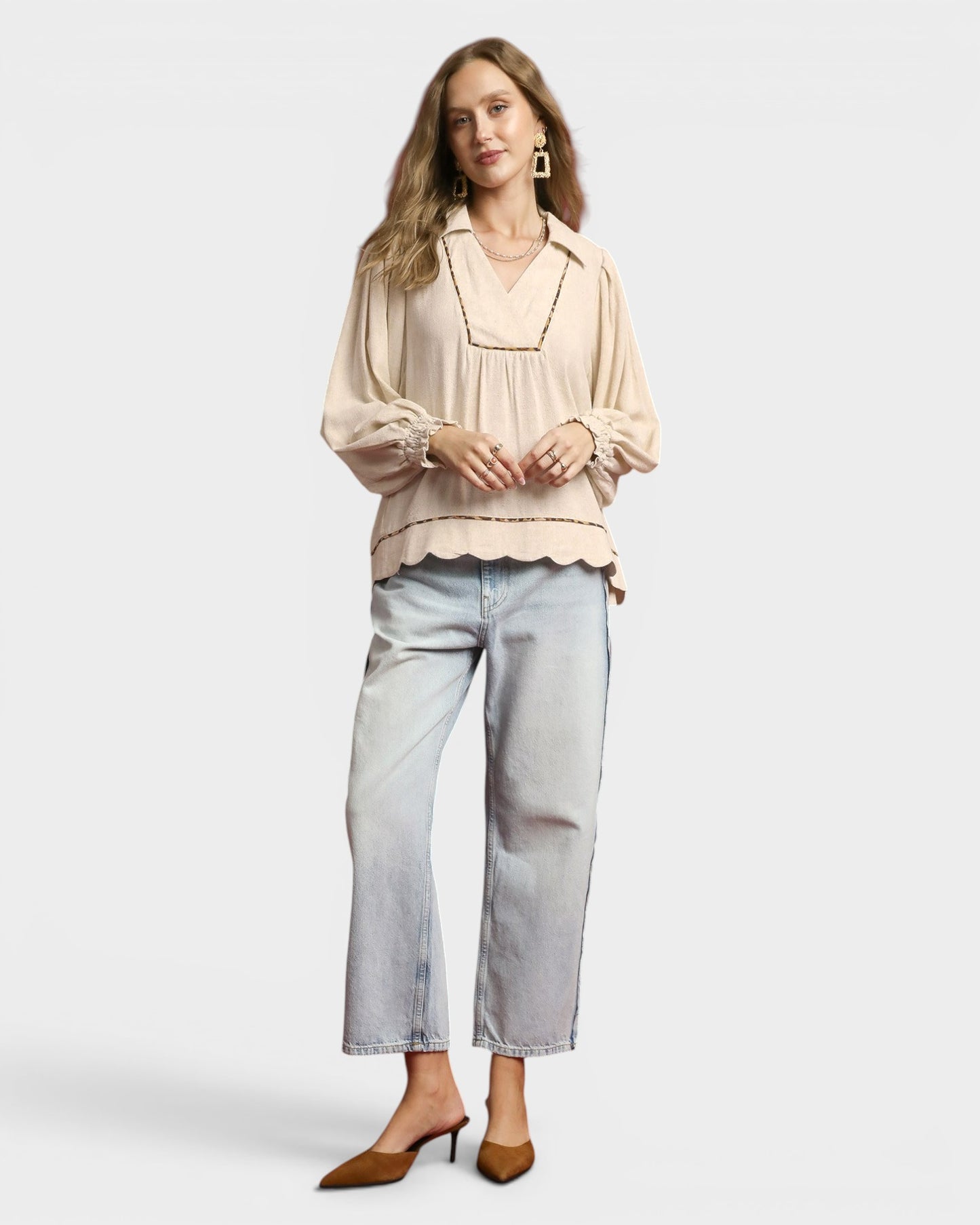 Woman wearing a beige blouse and light blue jeans on a white background