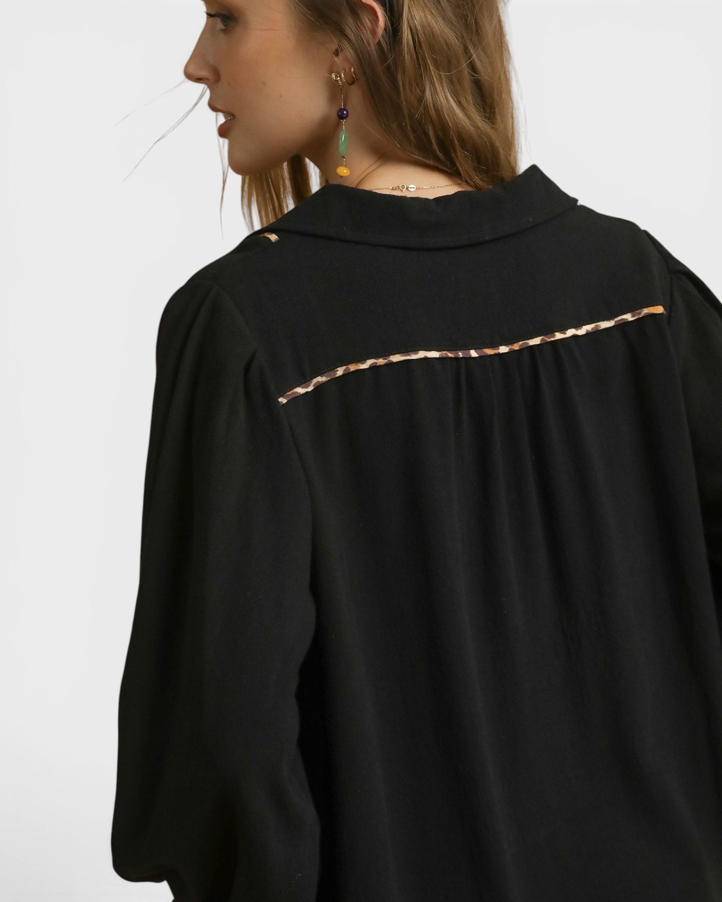 Black shirt with gold trim on a plain background