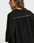 Black shirt with gold trim on a plain background