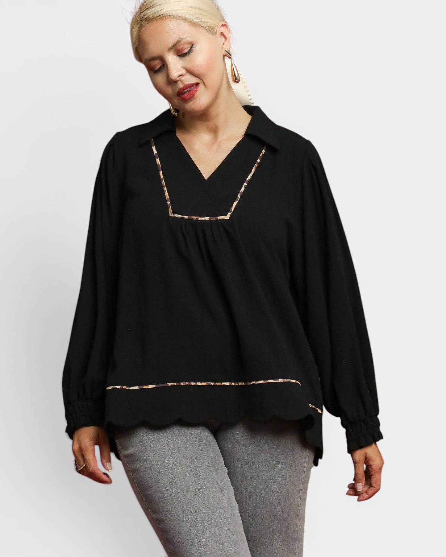 Woman wearing a black blouse with gold trim on a white background
