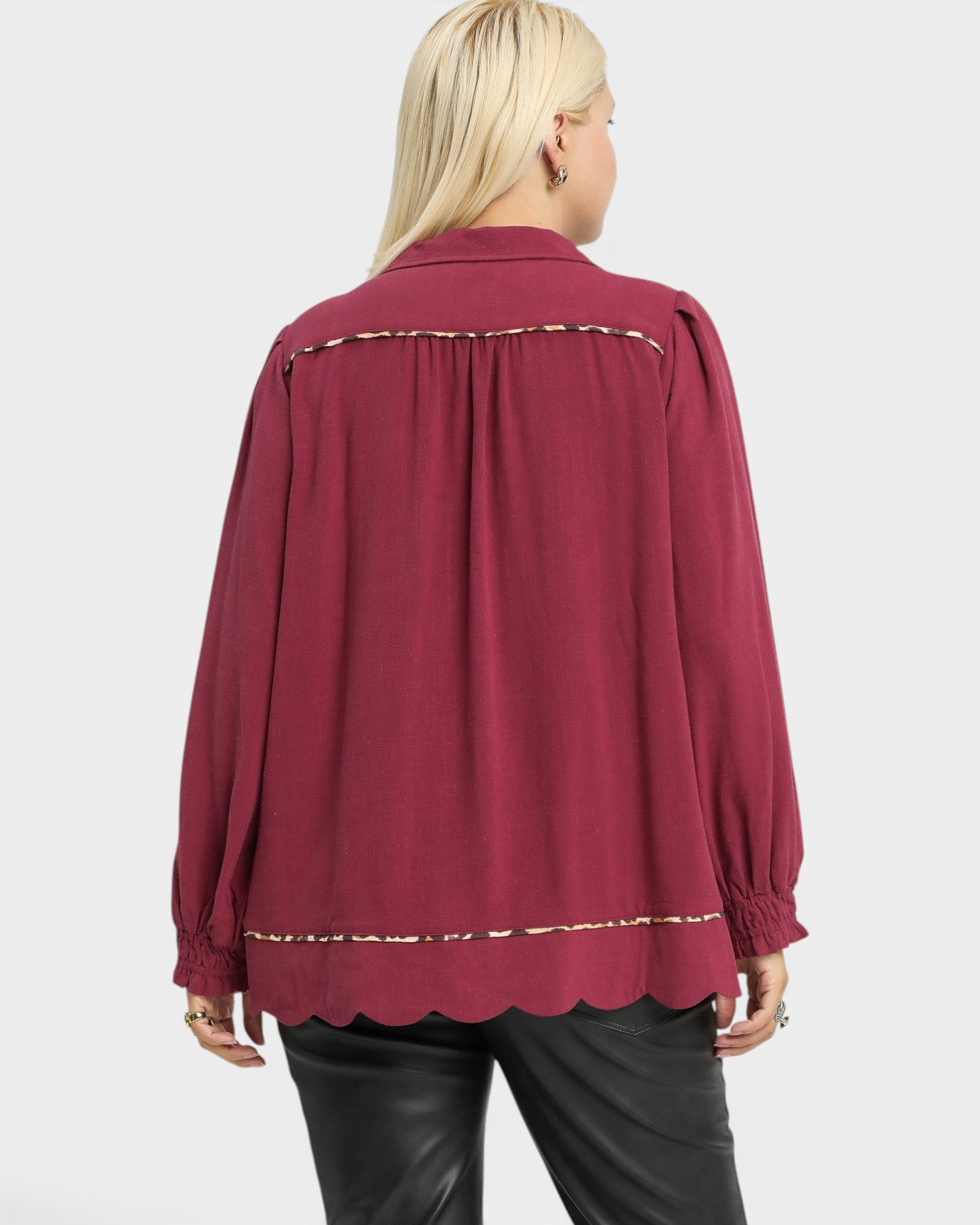Maroon blouse with scalloped hem on a white background