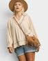 Woman wearing a beige blouse, denim shorts, and a brown hat with a matching bag on a light gray background