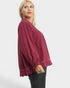 Woman wearing a burgundy blouse with gold trim on a white background