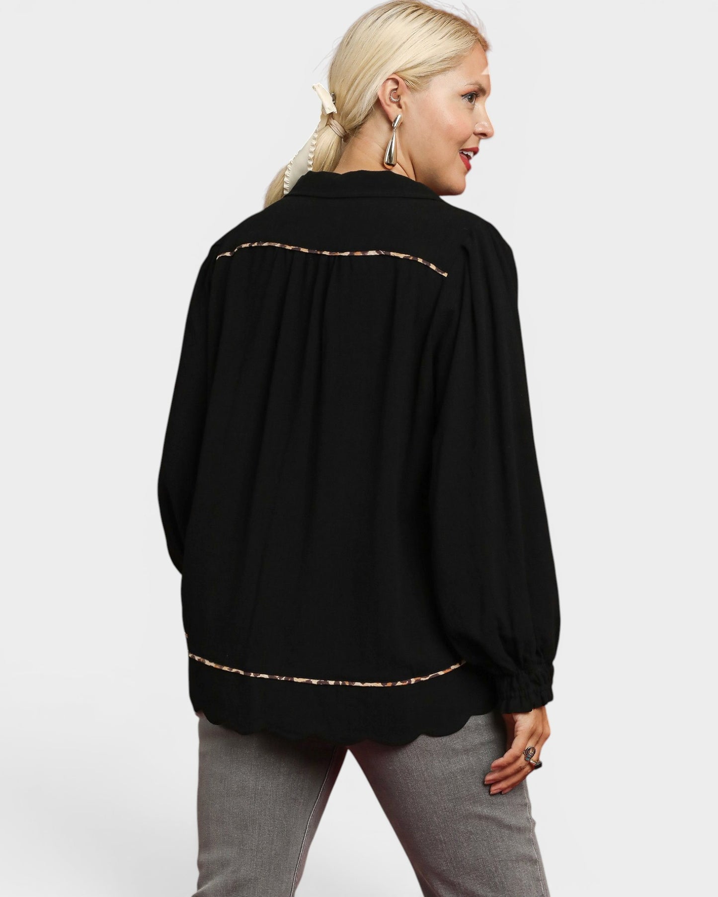 Woman wearing a black blouse with gold trim on a white background