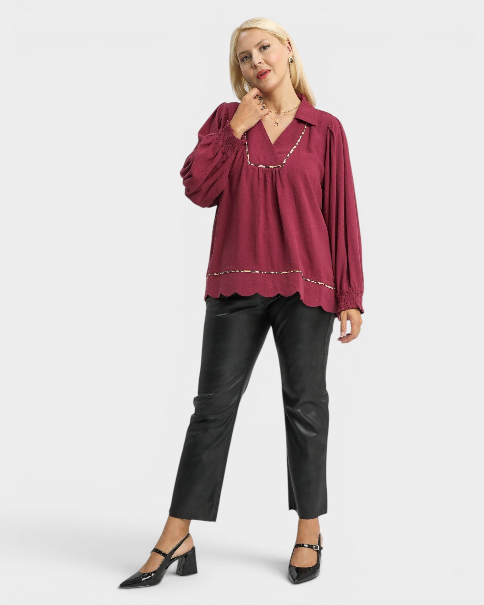Woman wearing a burgundy blouse and black pants on a white background