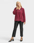 Woman wearing a burgundy blouse and black pants on a white background