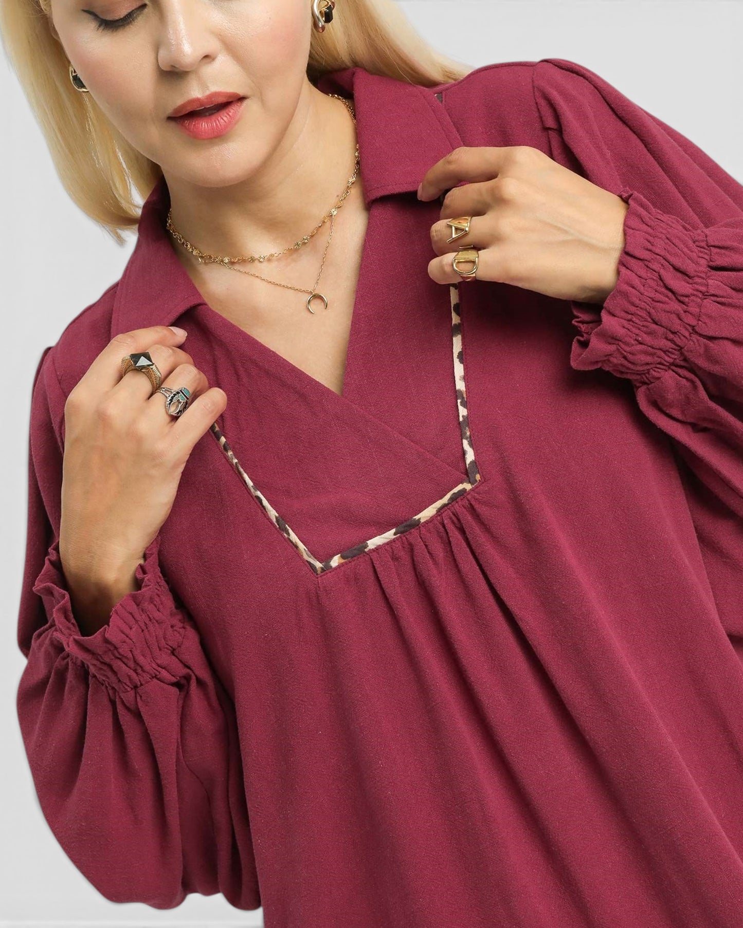 Woman wearing a burgundy blouse with a V-neckline on a white background