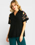 Woman wearing a black blouse with floral sleeves on a white background