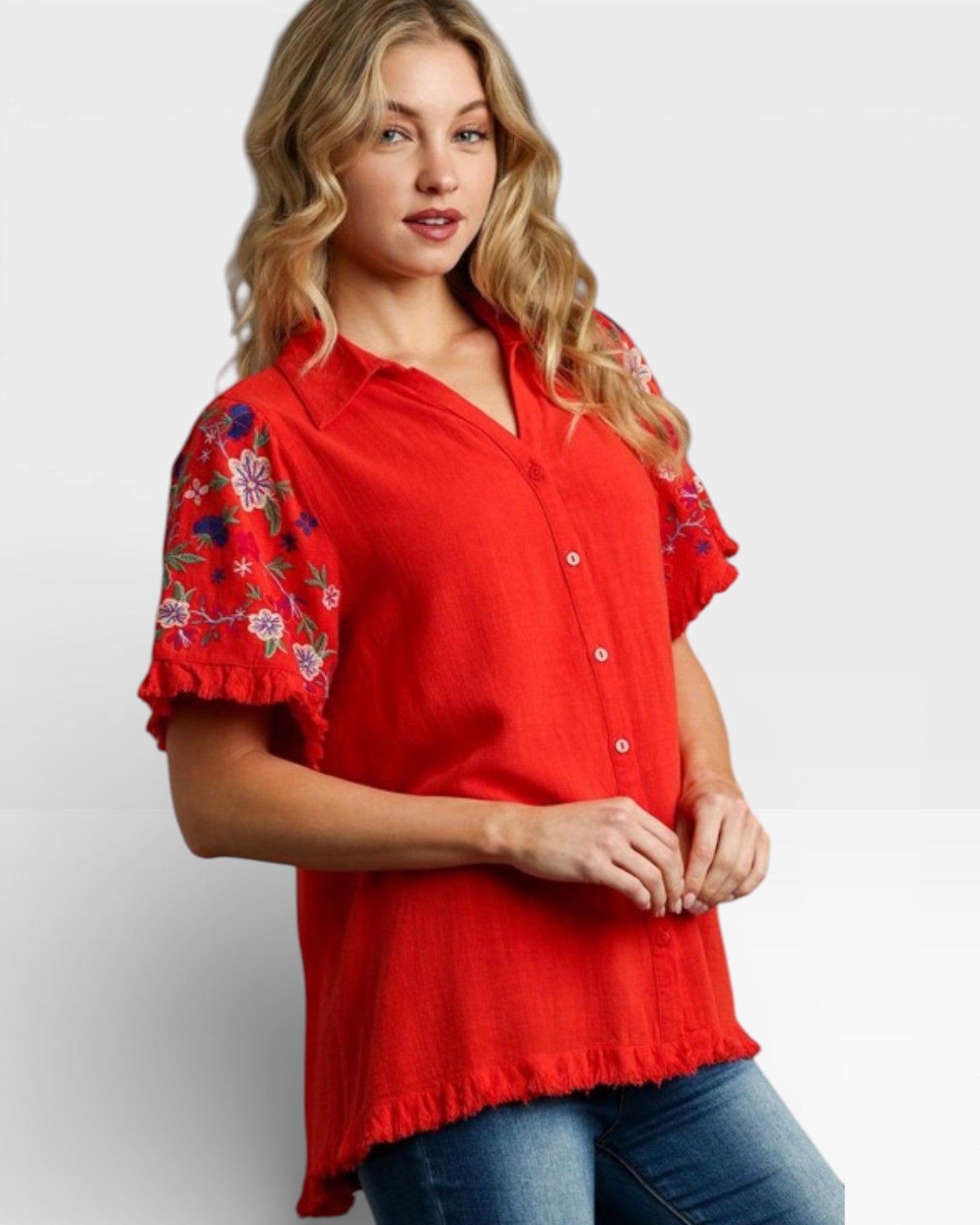 Woman wearing a red blouse with floral embroidery on sleeves against a white background