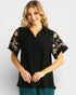 Woman wearing a black blouse with floral sleeves on a white background