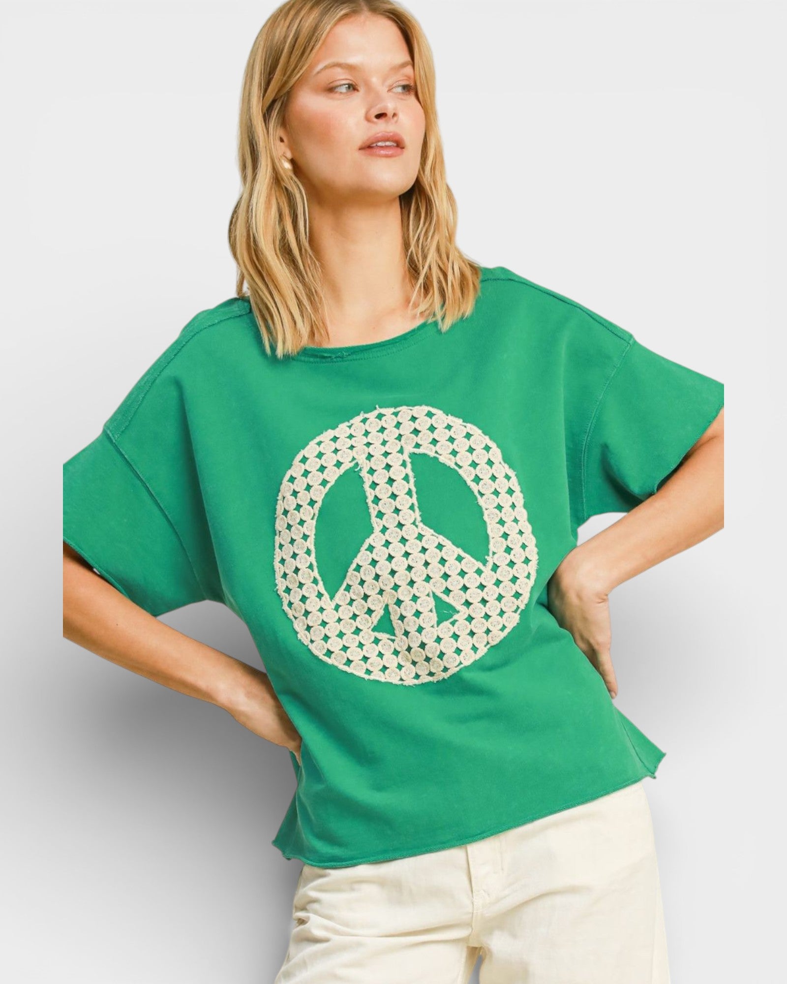 Woman wearing a green t-shirt with a peace symbol design on a plain background