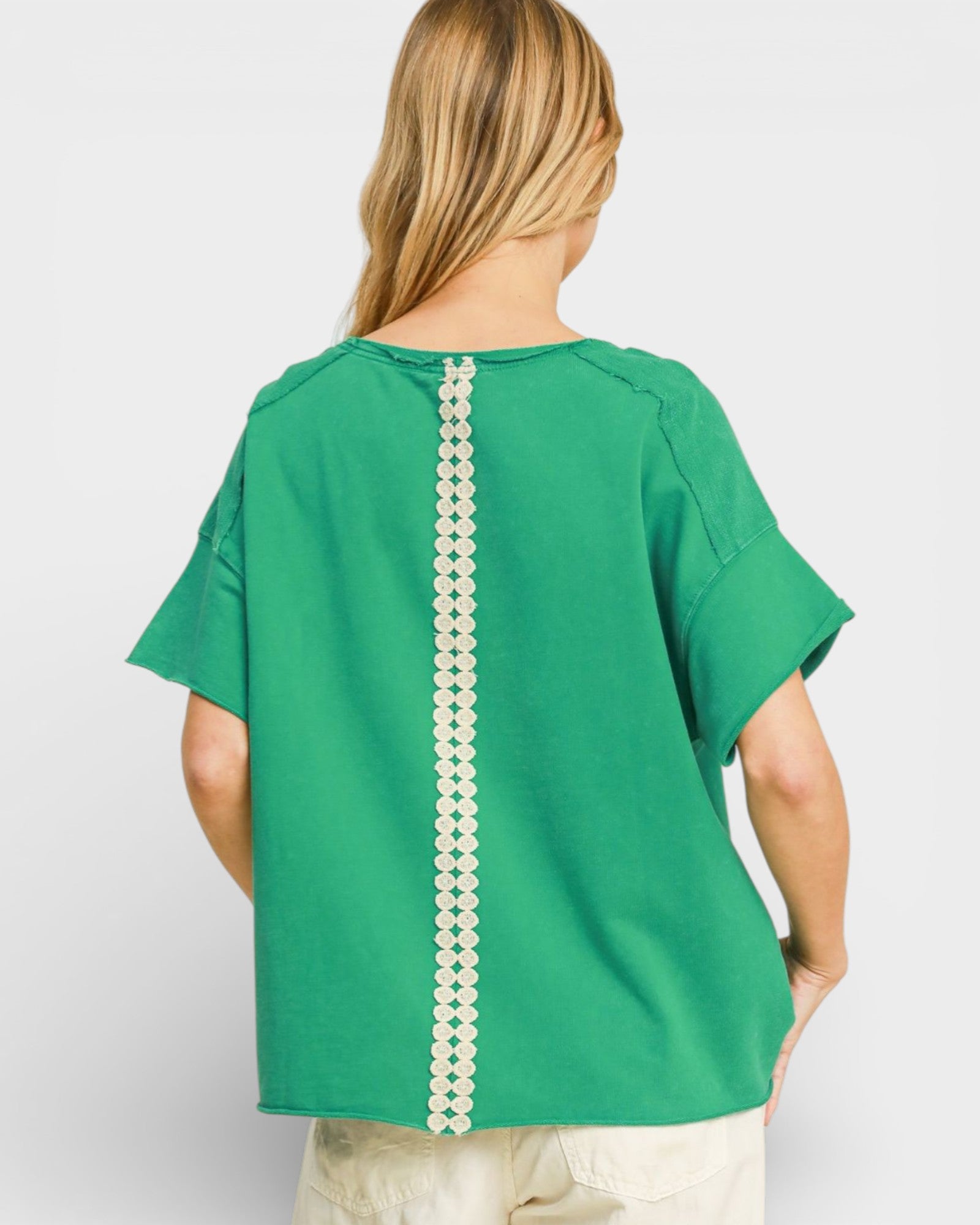 Green top with pearl embellishments on a plain background