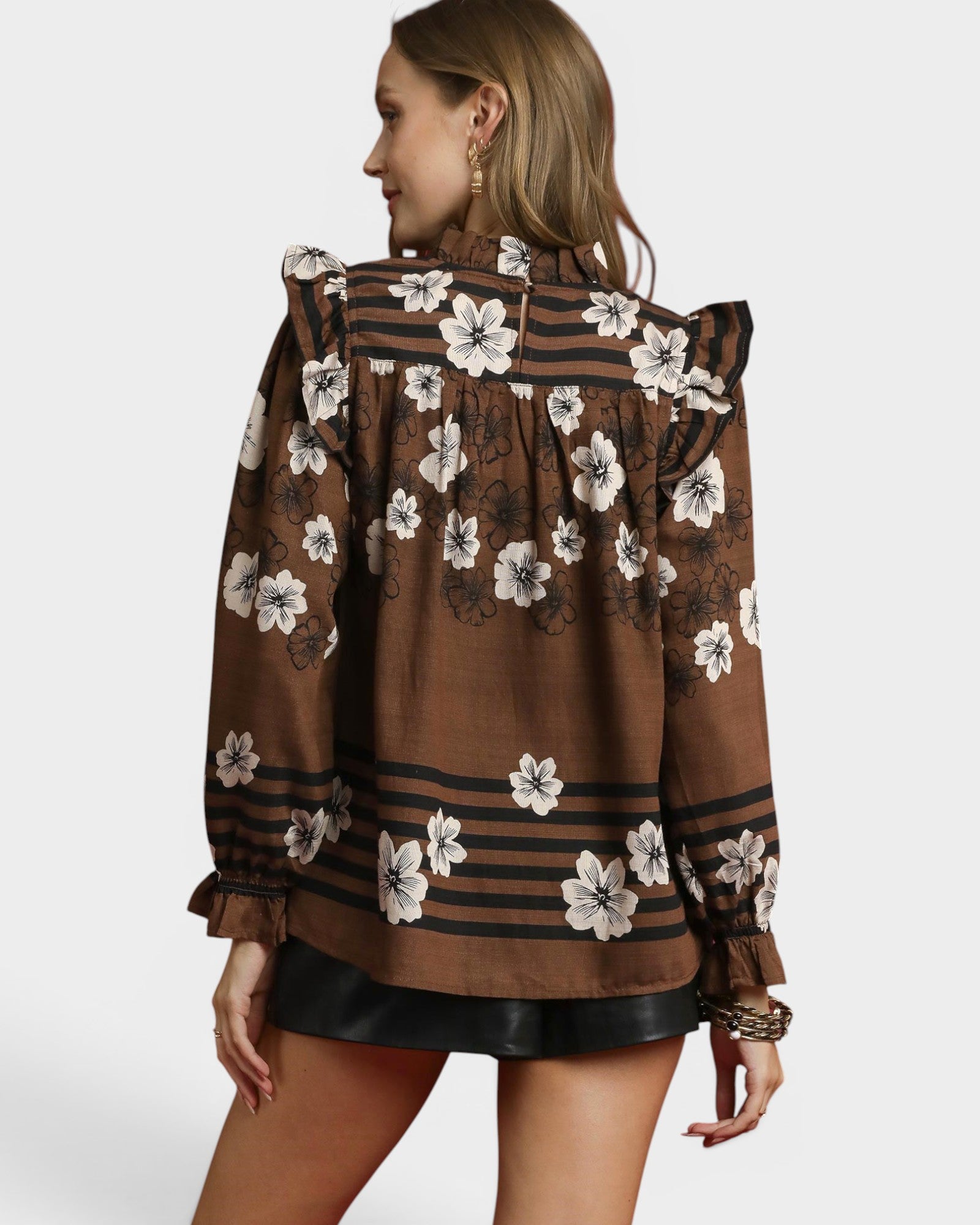 Woman wearing a brown floral blouse with a white background
