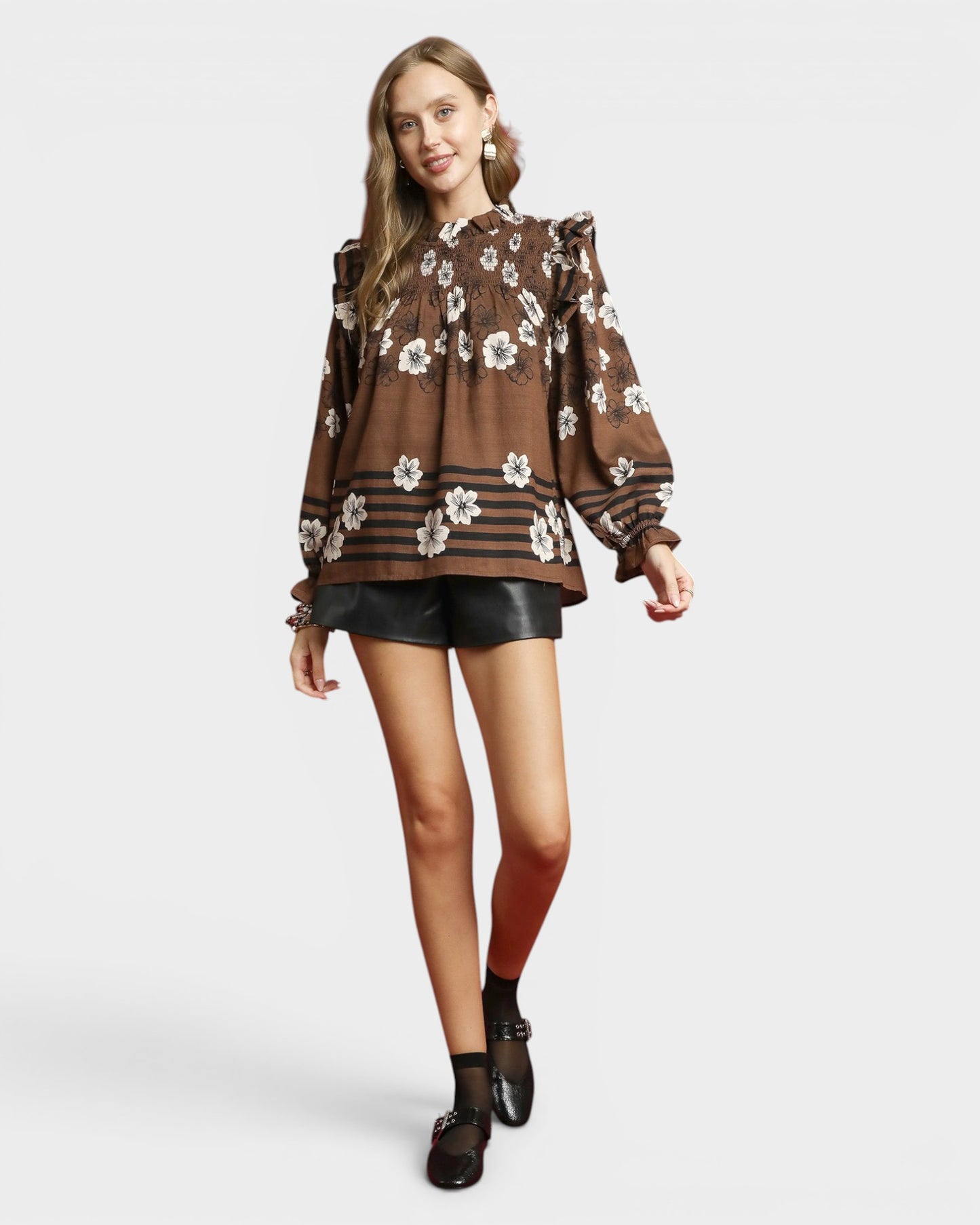 Woman wearing a brown floral blouse with black shorts on a white background