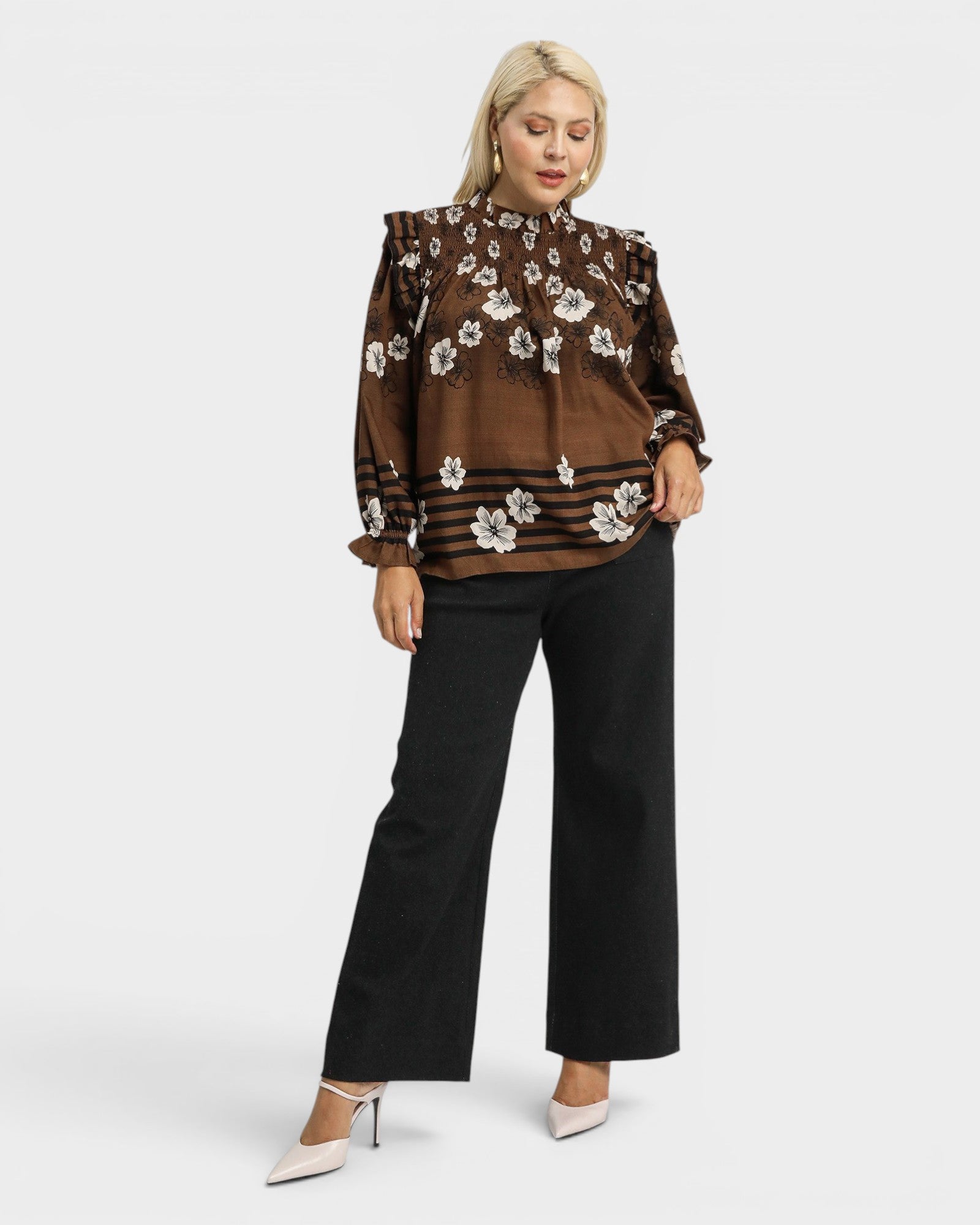 Woman wearing a brown floral blouse and black pants on a white background