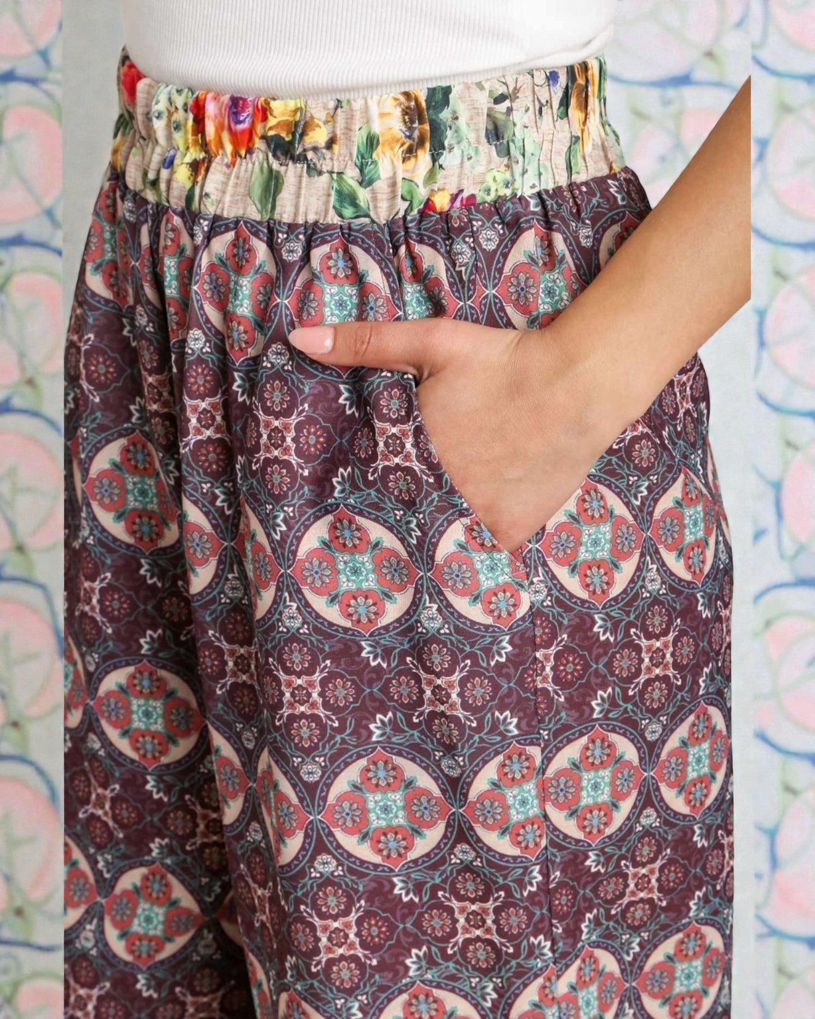 Colorful patterned pants with a hand touching the fabric against a multicolored background