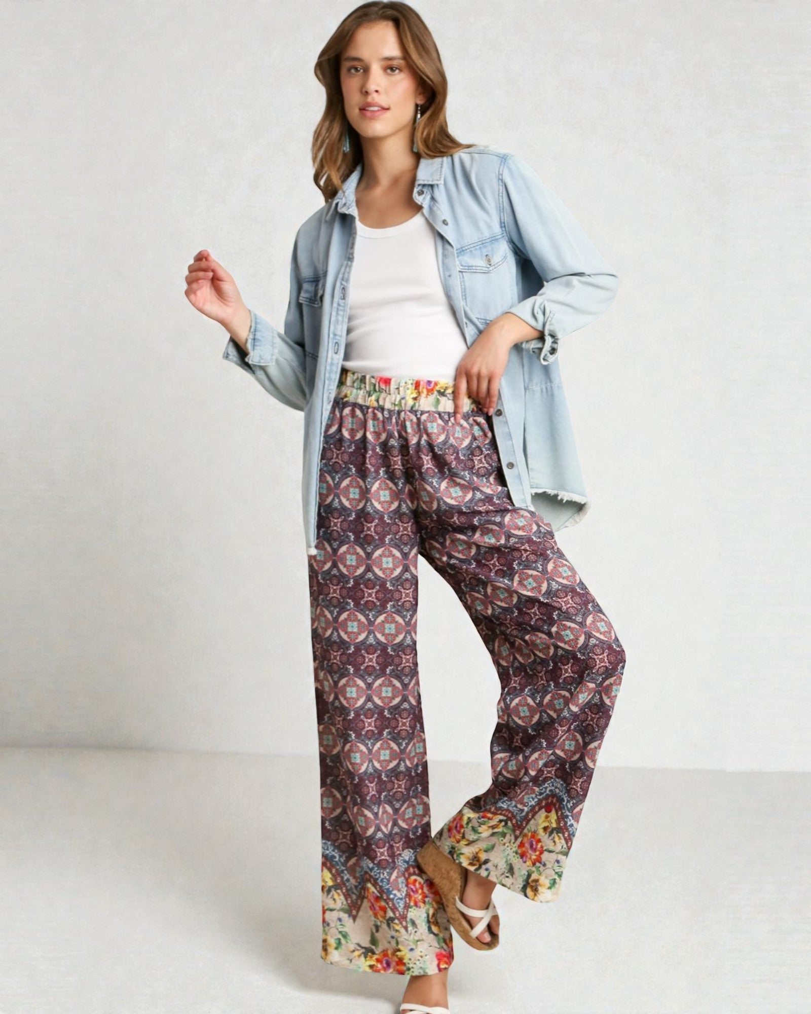 Woman wearing a denim jacket, white top, and patterned pants on a white background