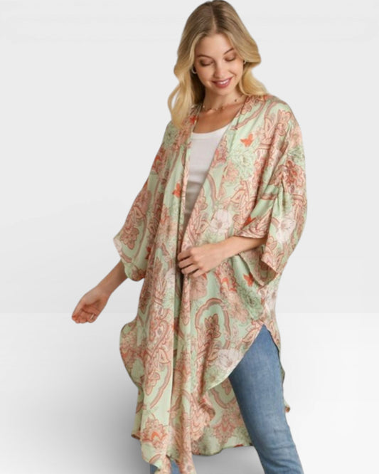 Woman wearing a floral kimono over a white top and blue jeans on a white background