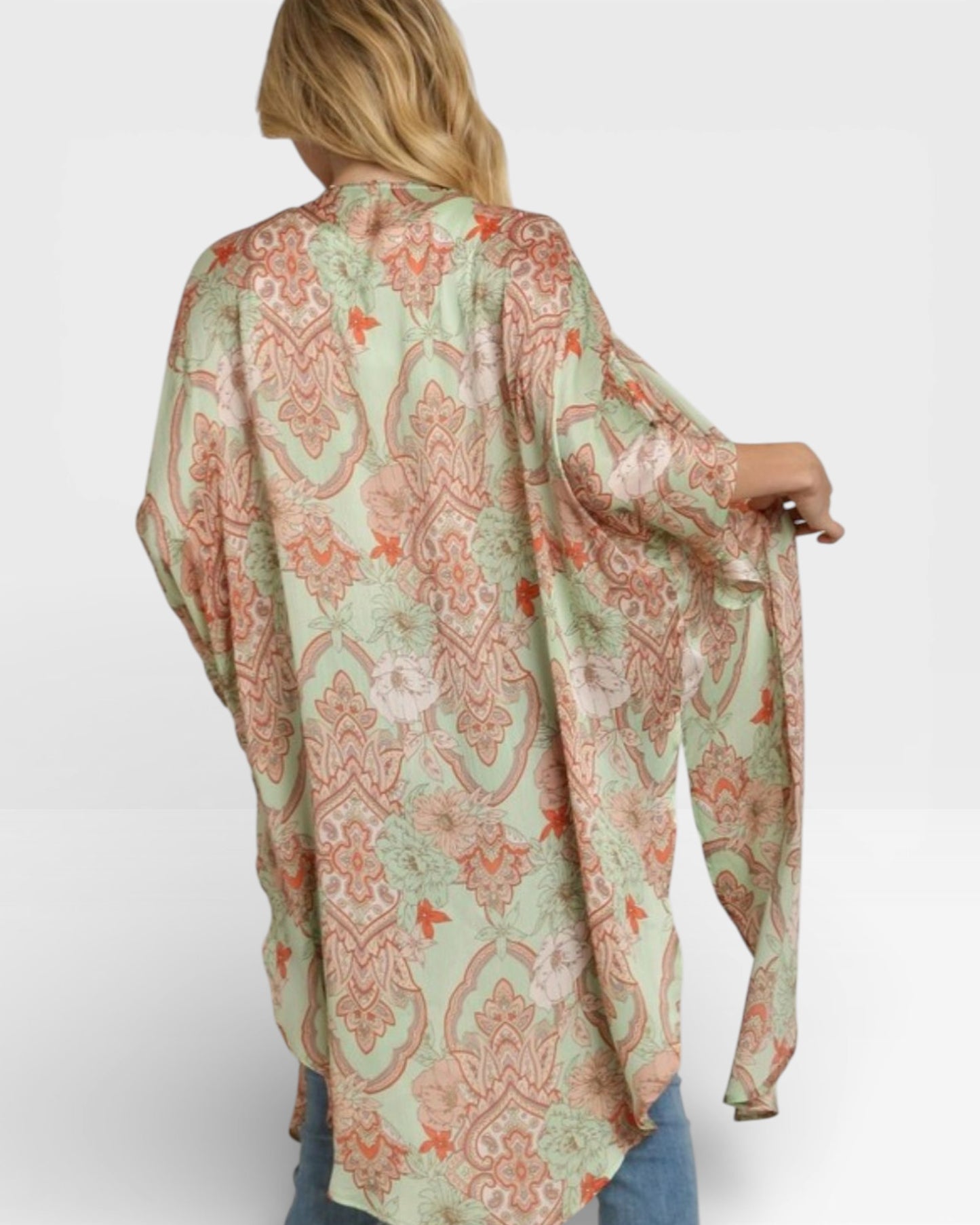 Woman wearing a patterned green and orange kimono-style top on a white background