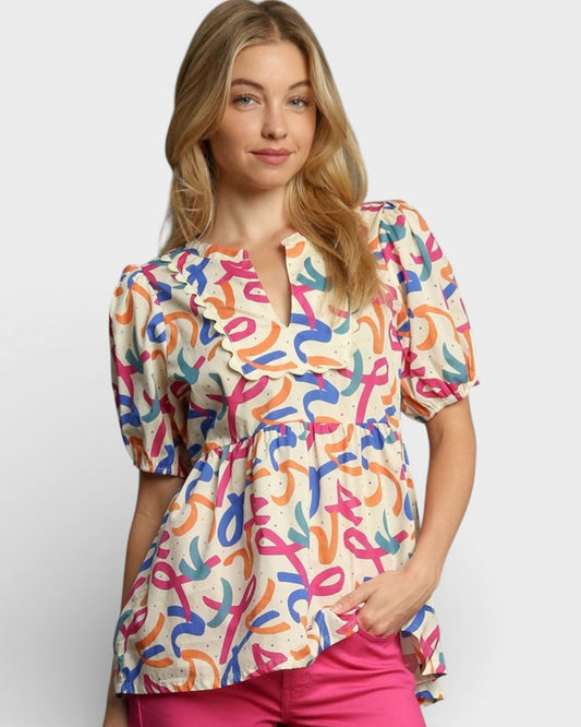 Woman wearing a colorful patterned blouse with pink pants on a white background