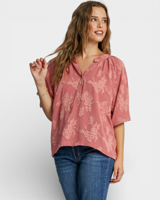 Woman wearing a pink floral blouse and blue jeans on a white background