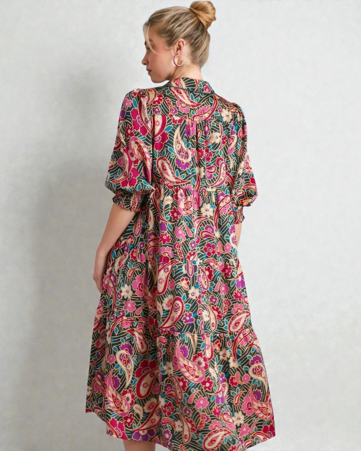 Woman wearing a colorful patterned dress against a plain background