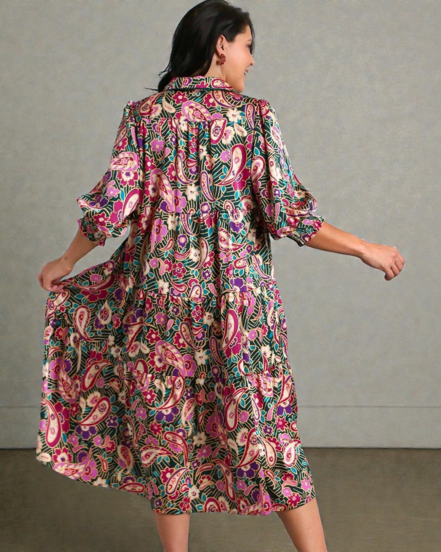 Woman wearing a colorful floral dress against a plain background