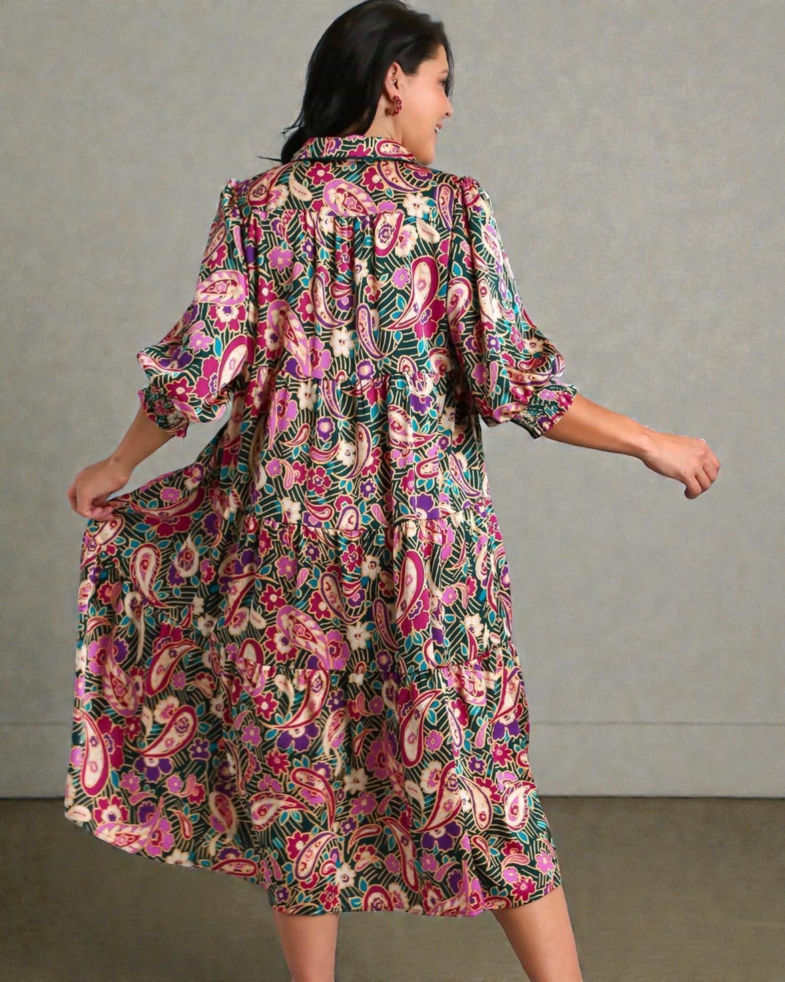 Woman wearing a colorful floral dress against a plain background