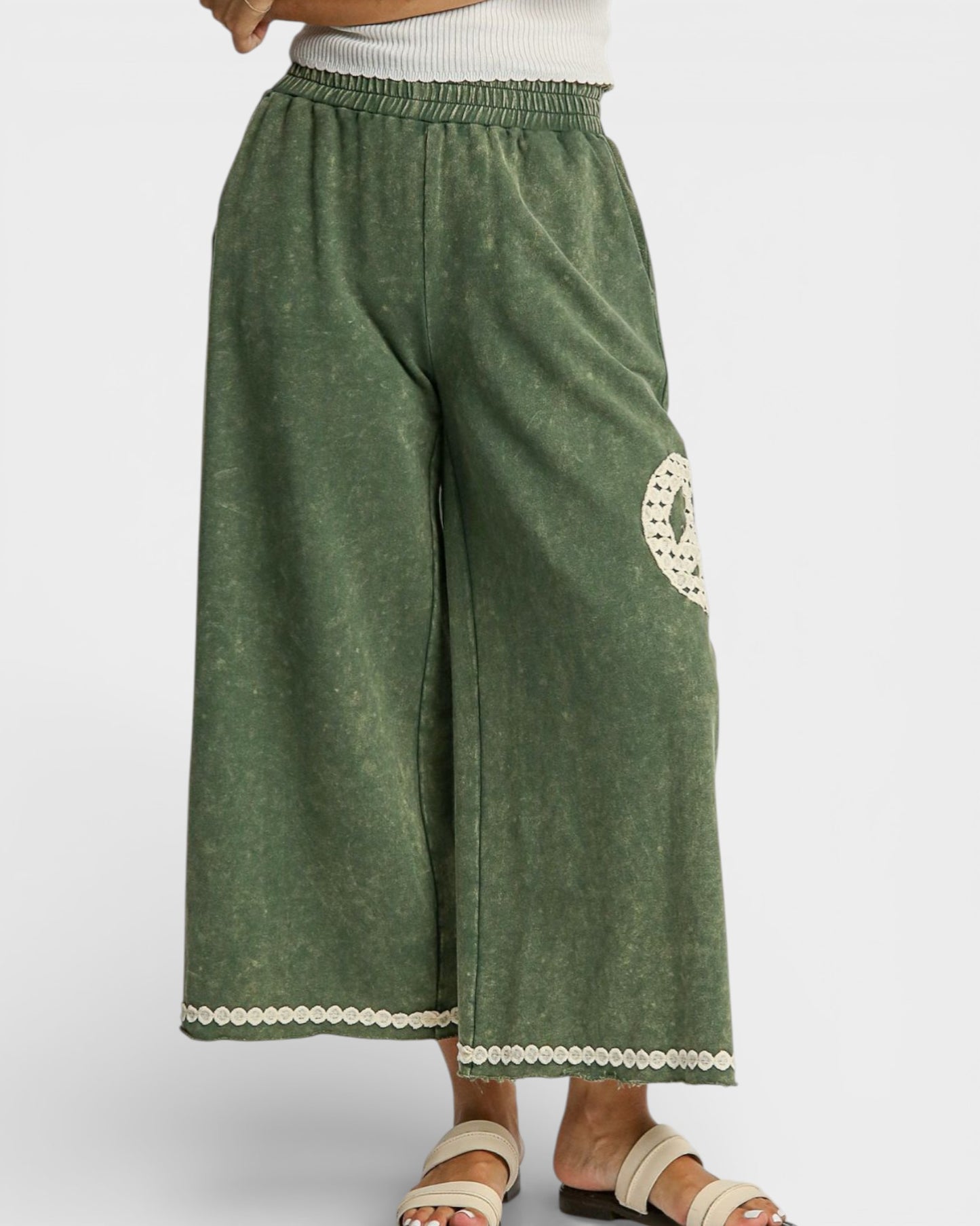 Green wide-leg pants with lace trim on a white background