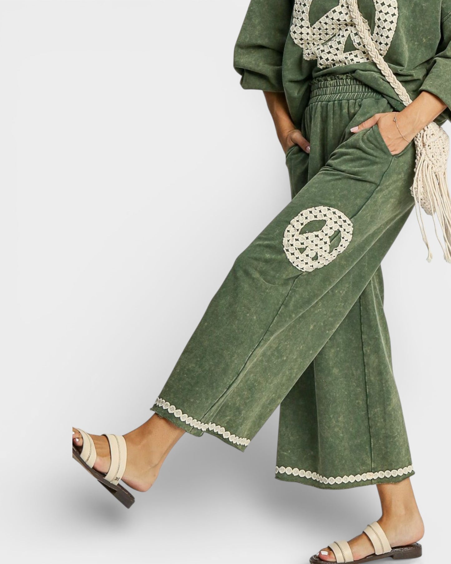 Green pants with lace trim worn by a person on a white background