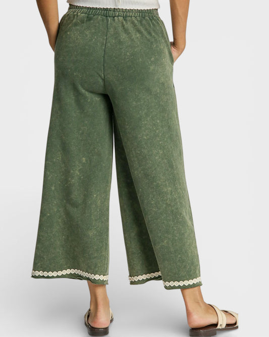 Green wide-leg pants with white trim on a plain background