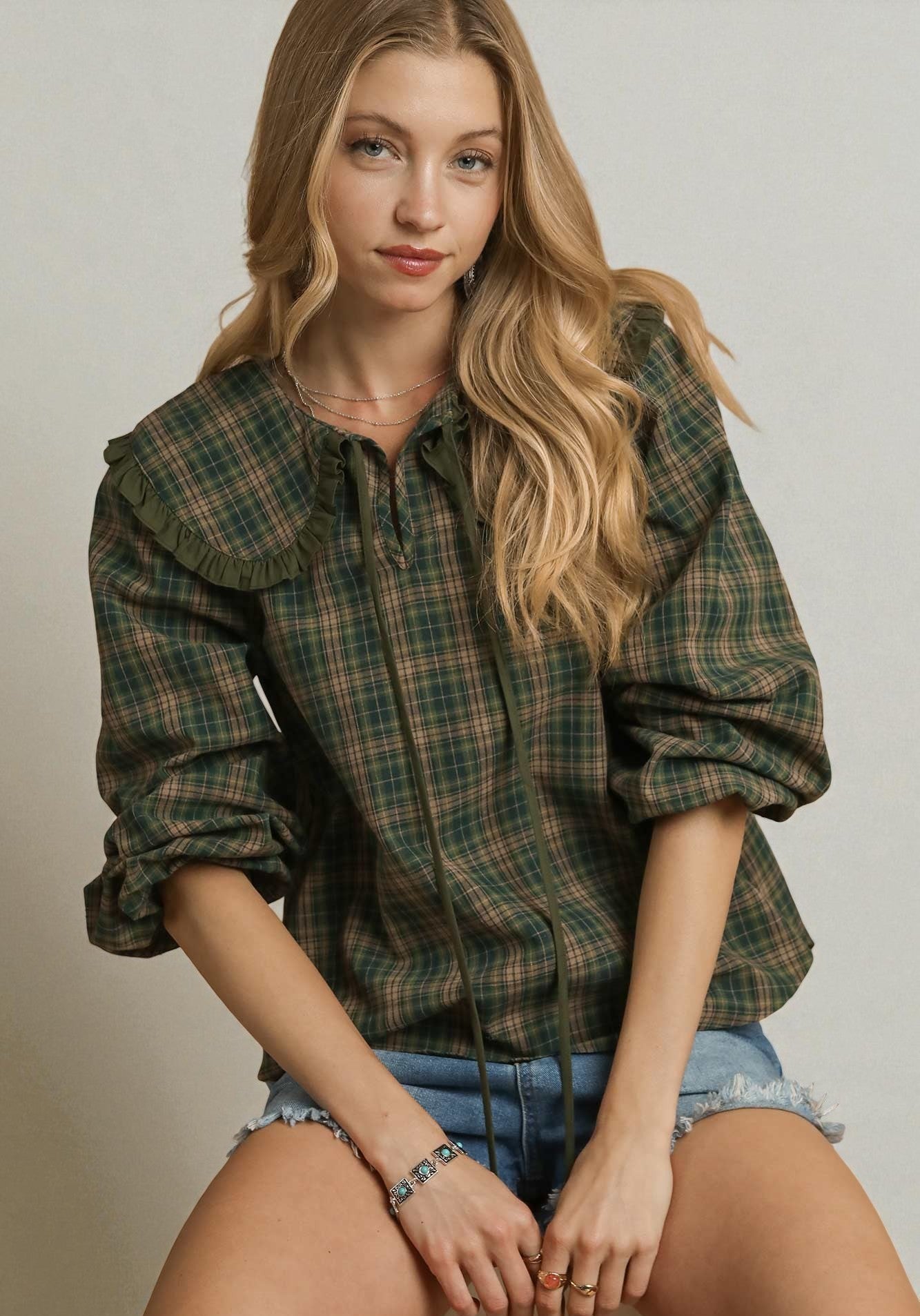 Woman wearing a plaid shirt and denim shorts on a plain background