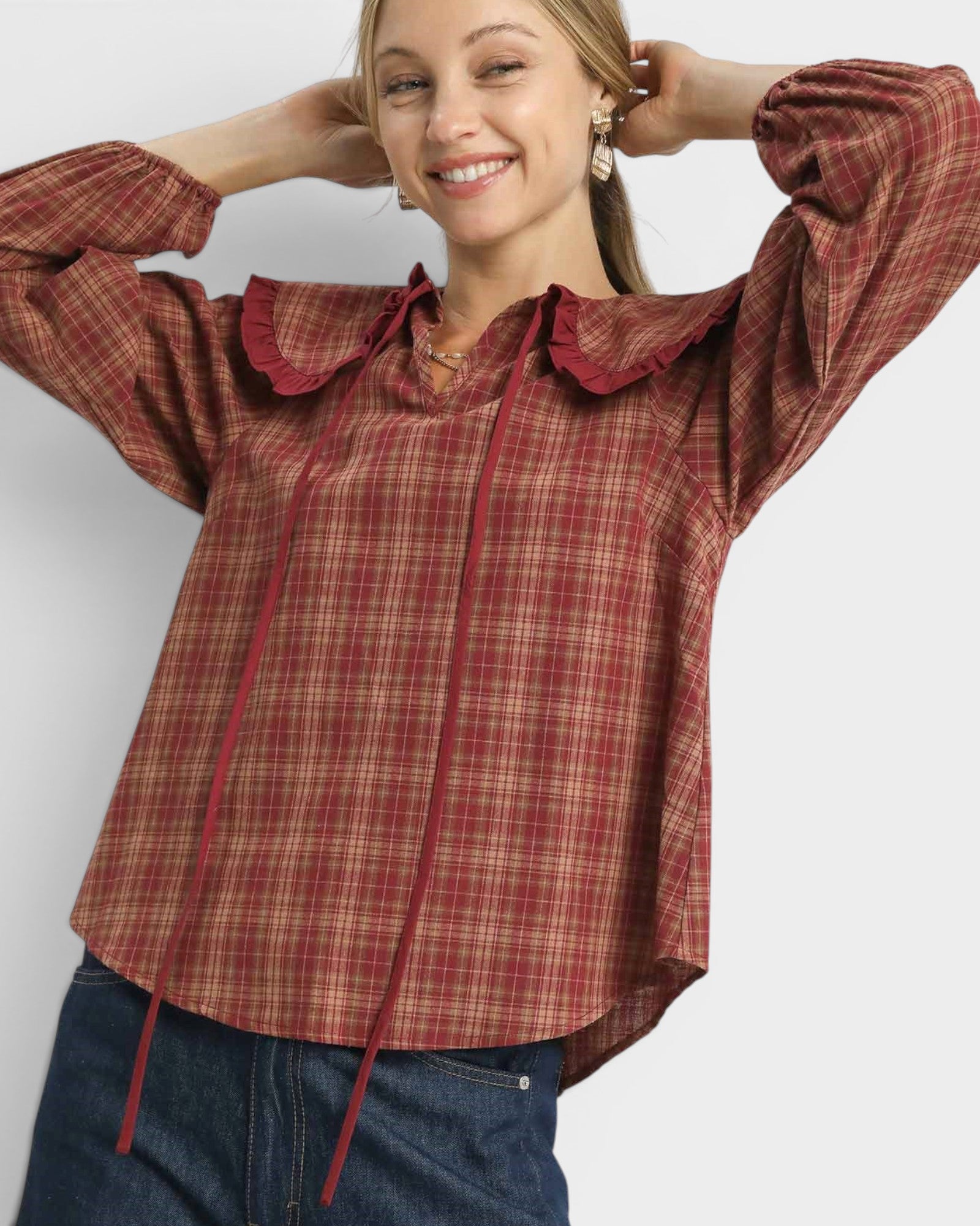 Woman wearing a red plaid shirt with a ruffled collar on a white background