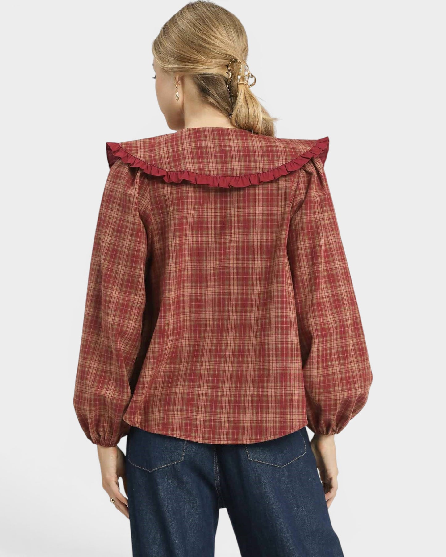 Person wearing a red plaid shirt with ruffled collar on a white background