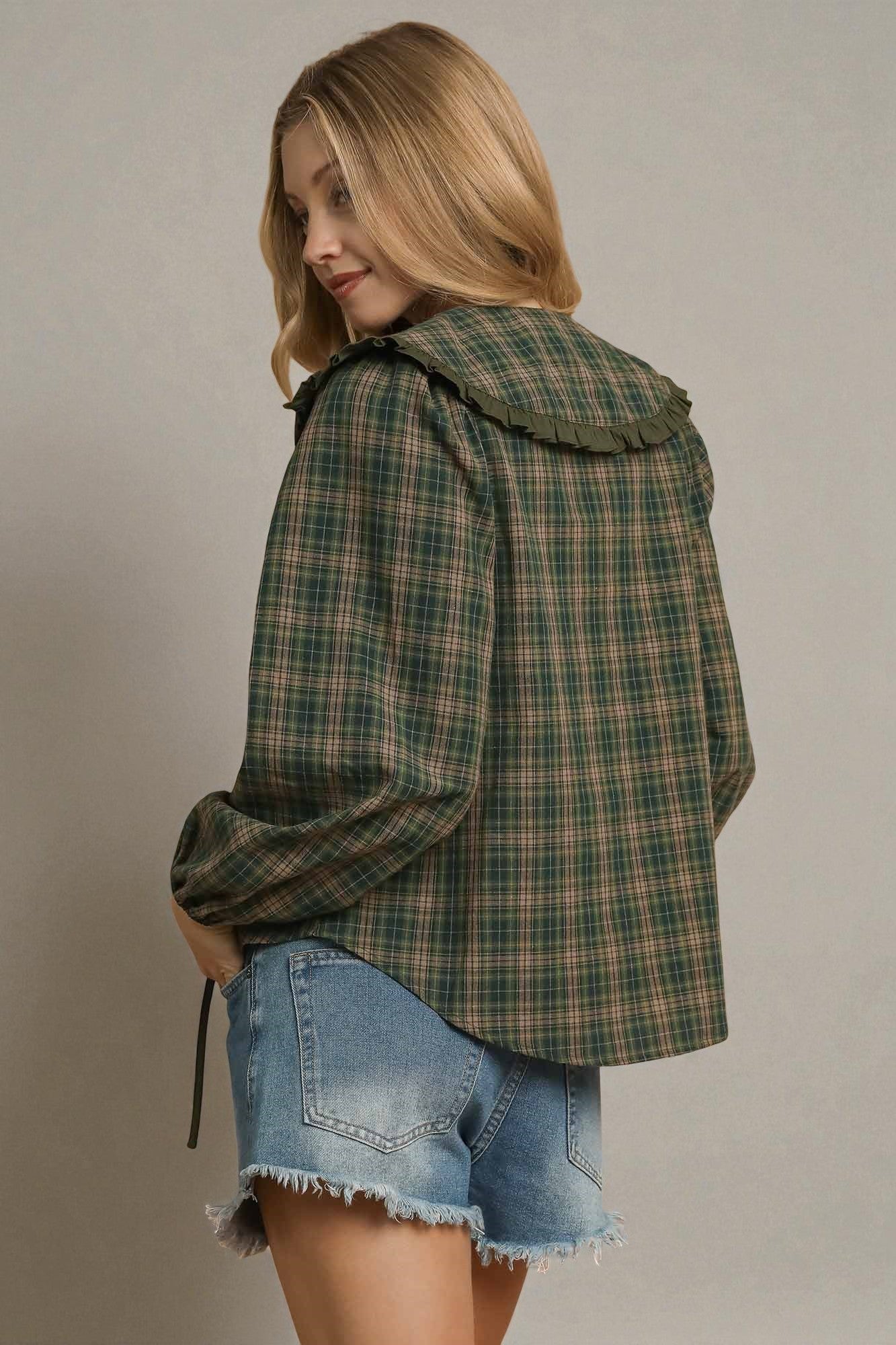 Woman wearing a plaid jacket and denim shorts on a plain background