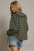 Woman wearing a plaid jacket and denim shorts on a plain background