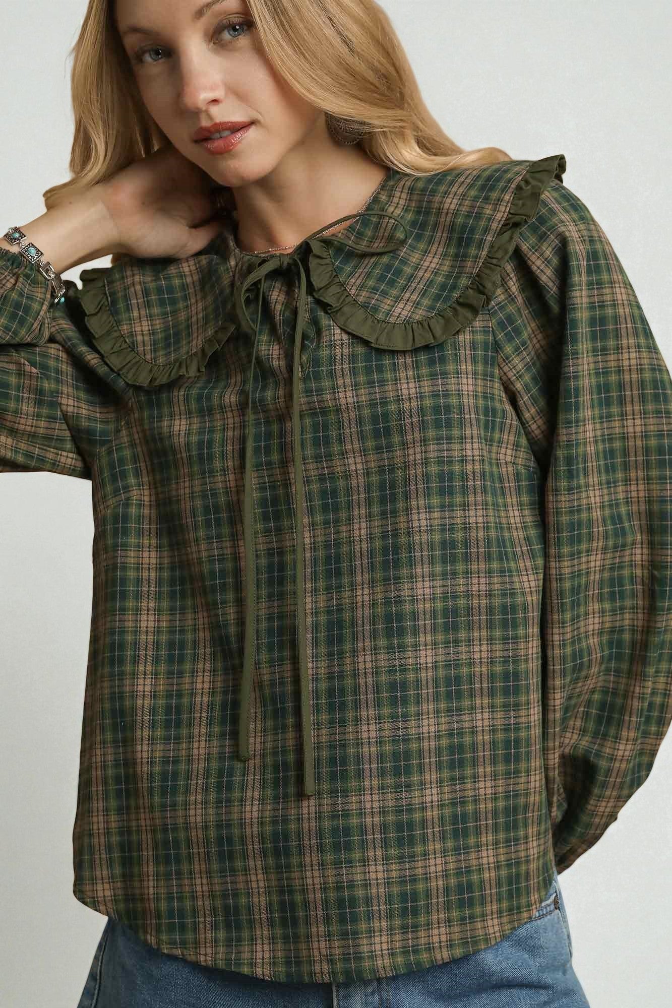 Woman wearing a green plaid shirt with a ruffled collar on a white background