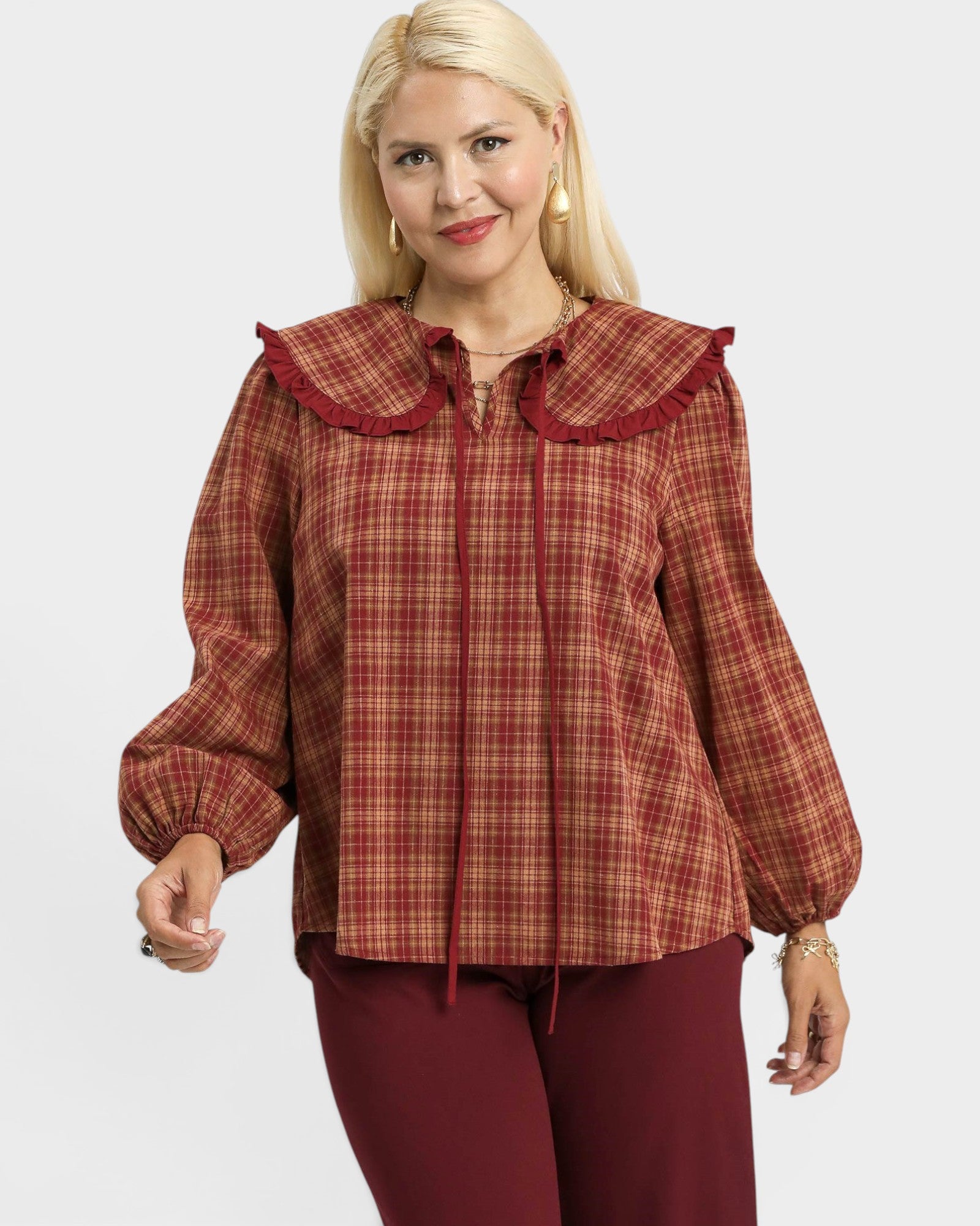 Woman wearing a red plaid blouse with a ruffled collar on a white background