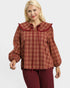 Woman wearing a red plaid blouse with a ruffled collar on a white background
