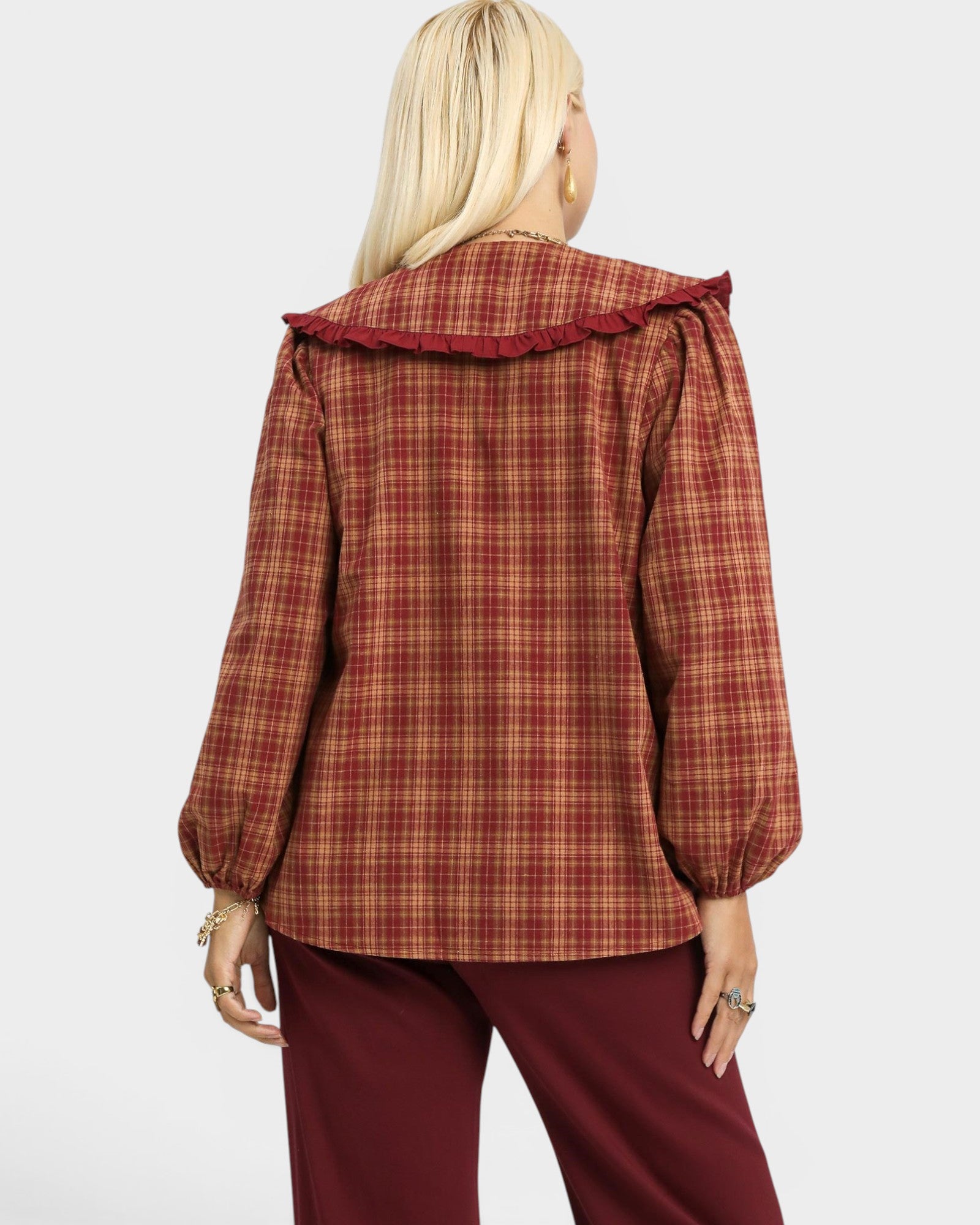 Person wearing a red plaid jacket with a ruffled collar on a white background