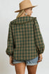 Person wearing a green plaid shirt and beige hat on a plain background