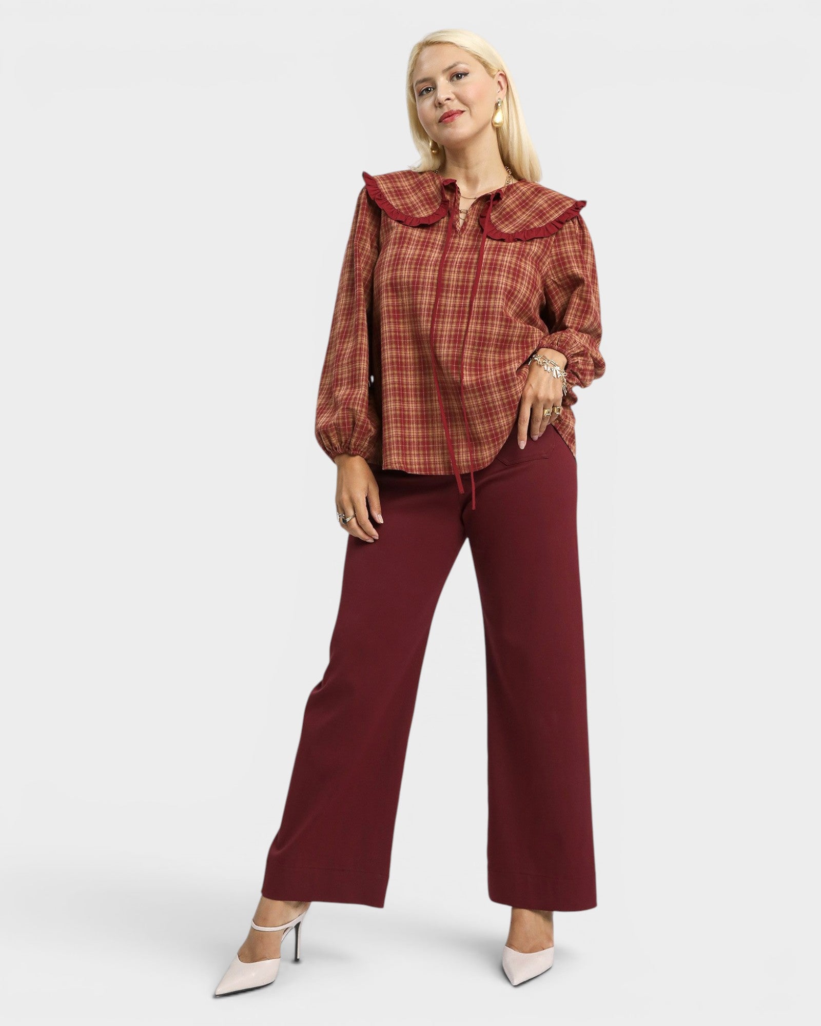 Woman wearing a plaid shirt and burgundy pants on a white background